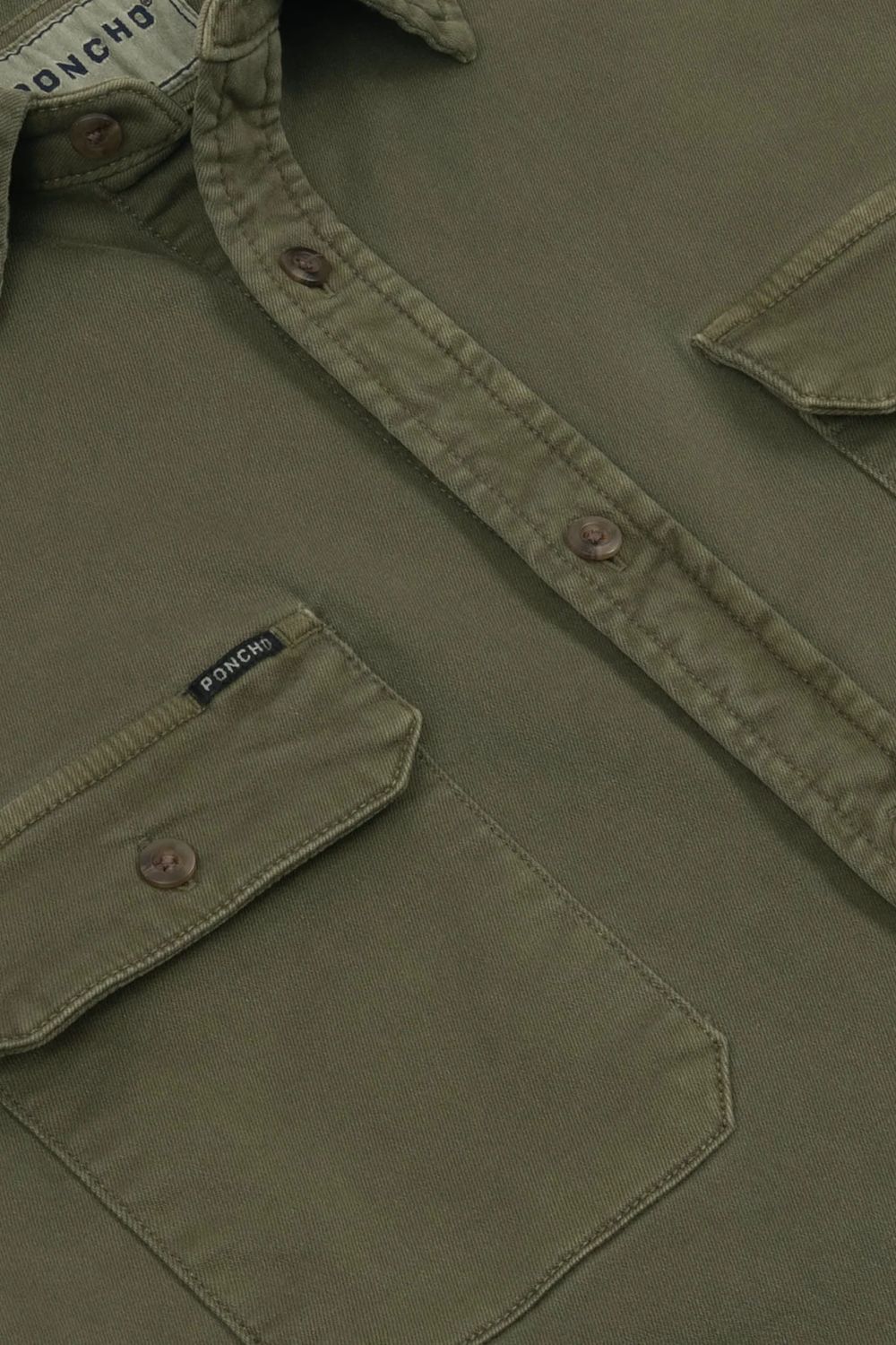 Close-up of an olive green button-up shirt by Poncho, showing the chest pocket, button closure, and inner neck label.