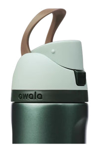 Owala FreeSip 24 oz stainless steel water bottle in winter green featuring a dark teal body, mint green lid, black push-button lock mechanism, and brown carrying loop.