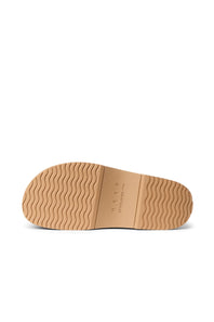 A close-up view of a tan rubber shoe sole with a wavy tread pattern, showing the brand name 'NEVER' and the text 'STOCKMANN' molded into the center, set against a plain white background.