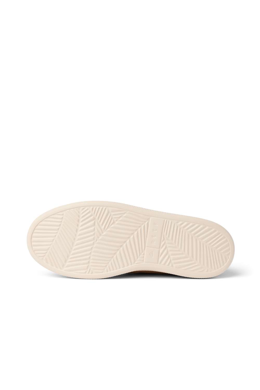 The cream-colored rubber outsole of a sneaker, showing a textured tread pattern, photographed from a top-down view on a white background.