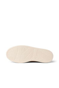 The cream-colored rubber outsole of a sneaker, showing a textured tread pattern, photographed from a top-down view on a white background.