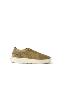 A low-top sneaker in olive green suede and tan leather panels with a thick off-white sole, shown from a side profile on a white background.
