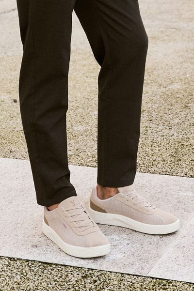 Man wearing black pants and tan Adyro sneakers on a sidewalk