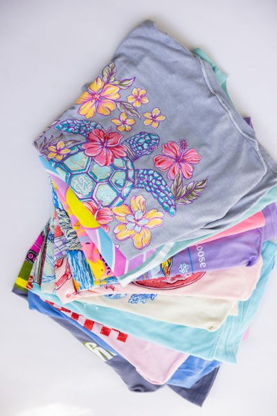 Different Simply Southern graphic t-shirts piled up on a plain background