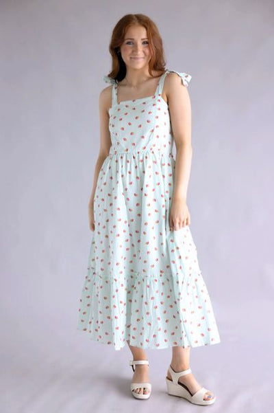 Woman wearing a light blue Simply Southern dress with small strawberry print in front of a plain background