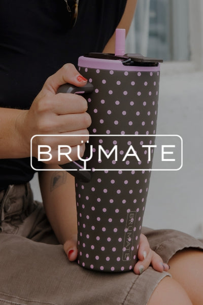 A person holding a brown with pink polka dots BruMate tumbler with a dark image overlay with BRUMATE text