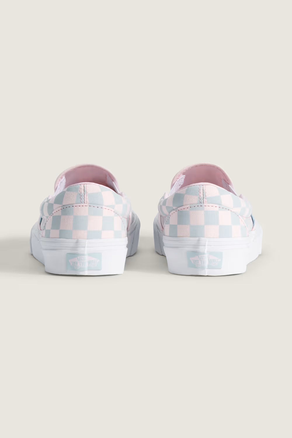 Vans Classic Slip-On Checkboard Shoes for Women in Pastel Pink/Dawn MistPair of checkered slip-on shoes on a light background 