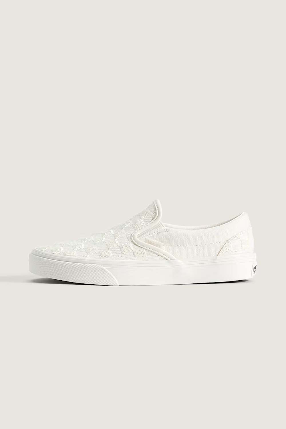 A single white slip-on platform sneaker with a subtle embossed pattern on the upper, shown in profile against a solid light beige background.