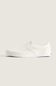 A single white slip-on platform sneaker with a subtle embossed pattern on the upper, shown in profile against a solid light beige background.
