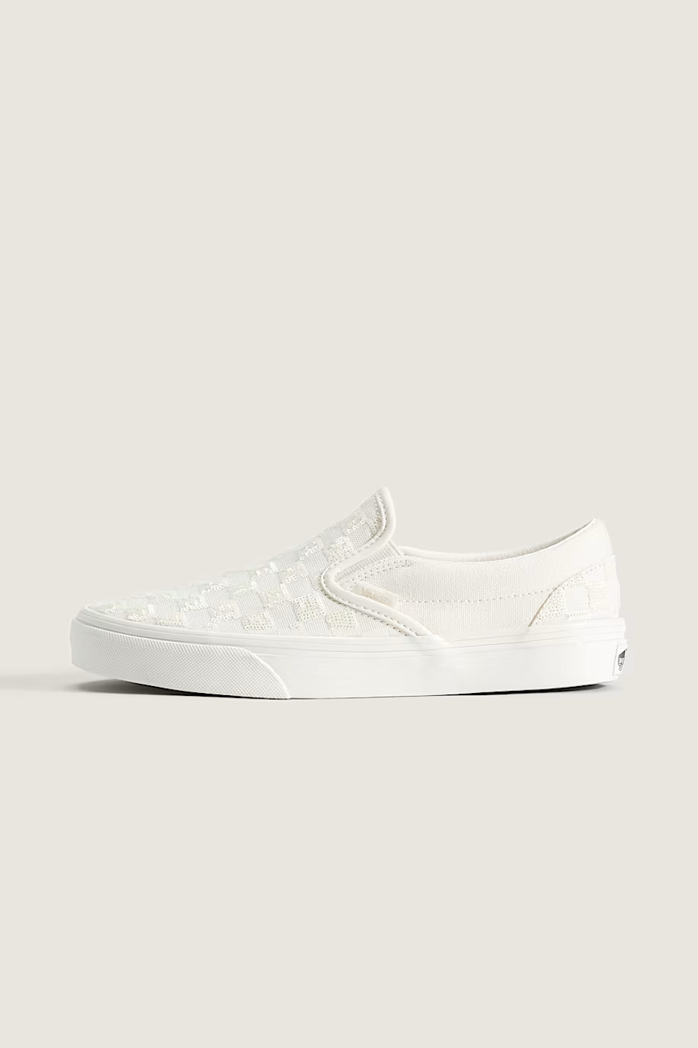 A single white slip-on platform sneaker with a subtle embossed pattern on the upper, shown in profile against a solid light beige background.