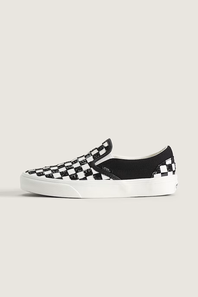 A single Vans slip-on platform sneaker in a black and white checkerboard pattern, shown from the side against a light beige background.