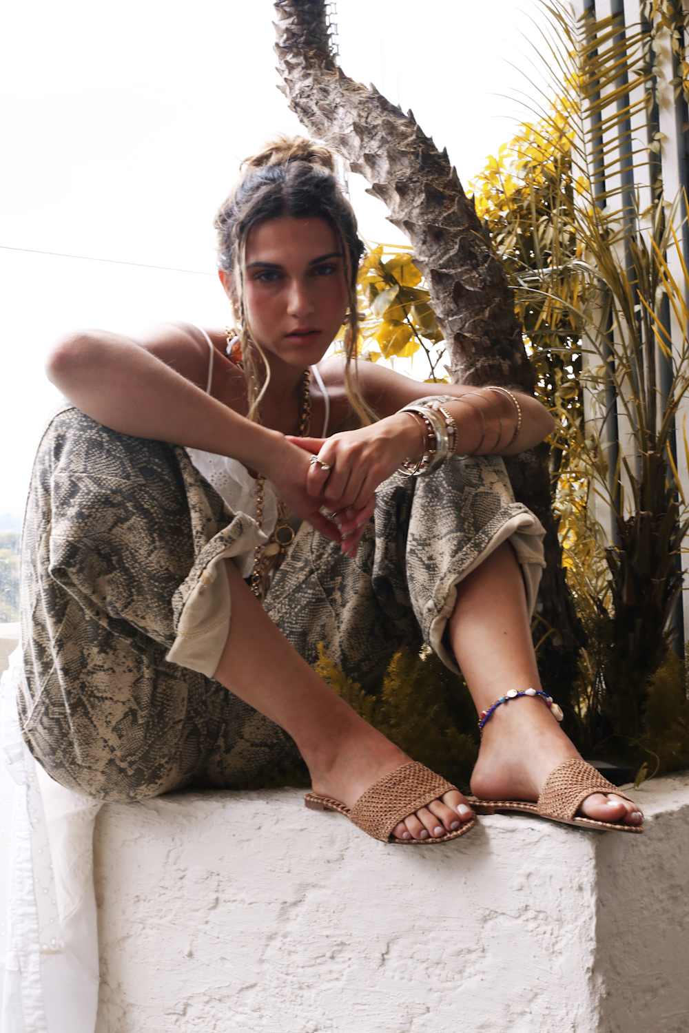 Woman sitting on a ledge with plants in the background