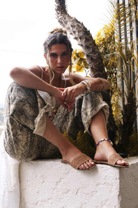 Woman sitting on a ledge with plants in the background