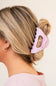 Woman with a pink hair clip in her bun against a beige background