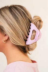 Woman with a pink hair clip in her bun against a beige background