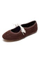 A dark brown suede ballet flat shoe with a white bow detail across the vamp, shown on a plain white background.