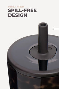 Close-up of a tumbler with a dark gray spill-free straw lid and a marbled dark brown body on a light gray background, with text reading 'EVERYDAY TUMBLER SPILL-FREE DESIGN'.