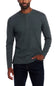 A man wearing a dark gray long-sleeve henley shirt and dark blue jeans, standing against a plain white background.