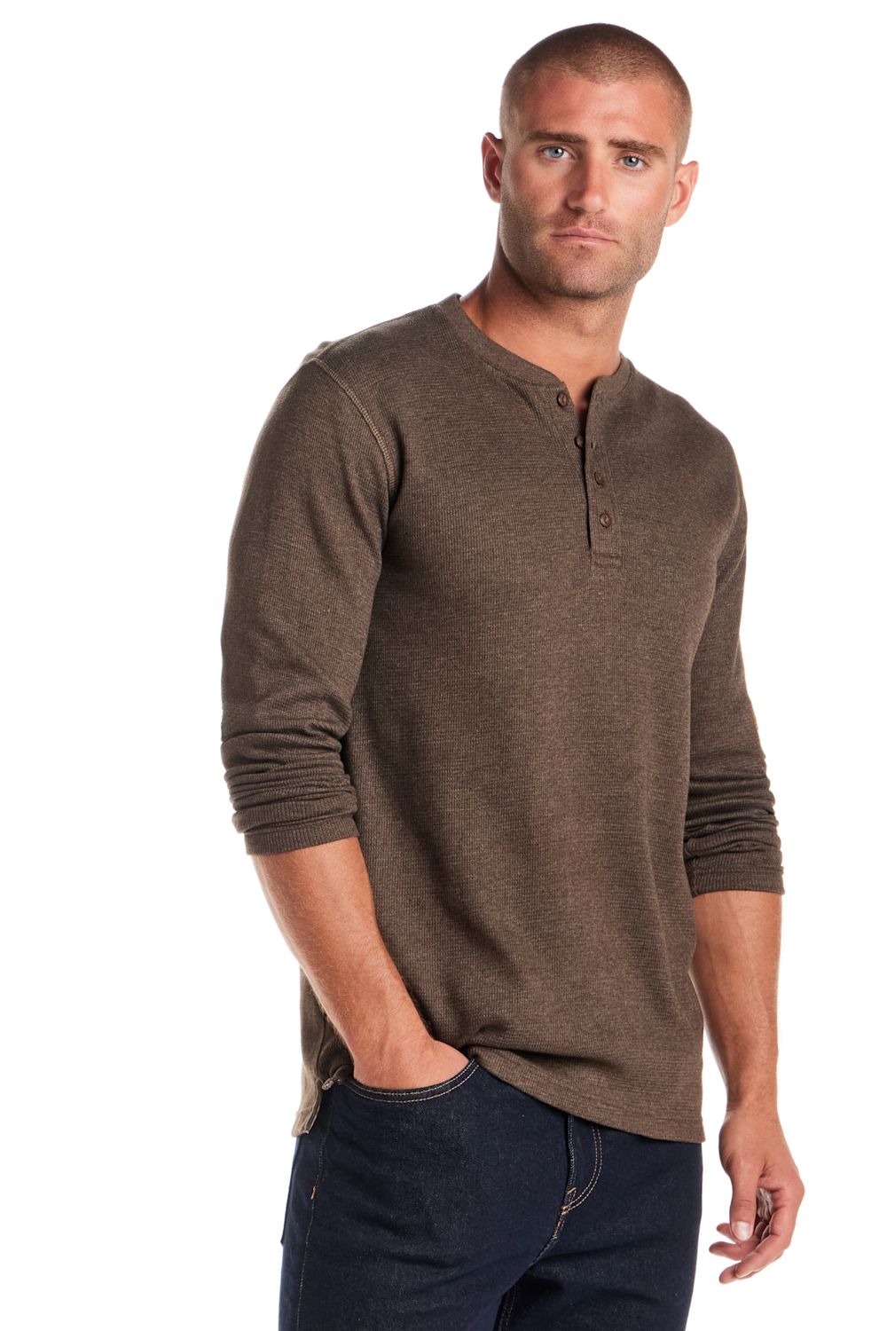 A man wearing a brown long-sleeve henley shirt and dark blue jeans, standing against a plain white background.