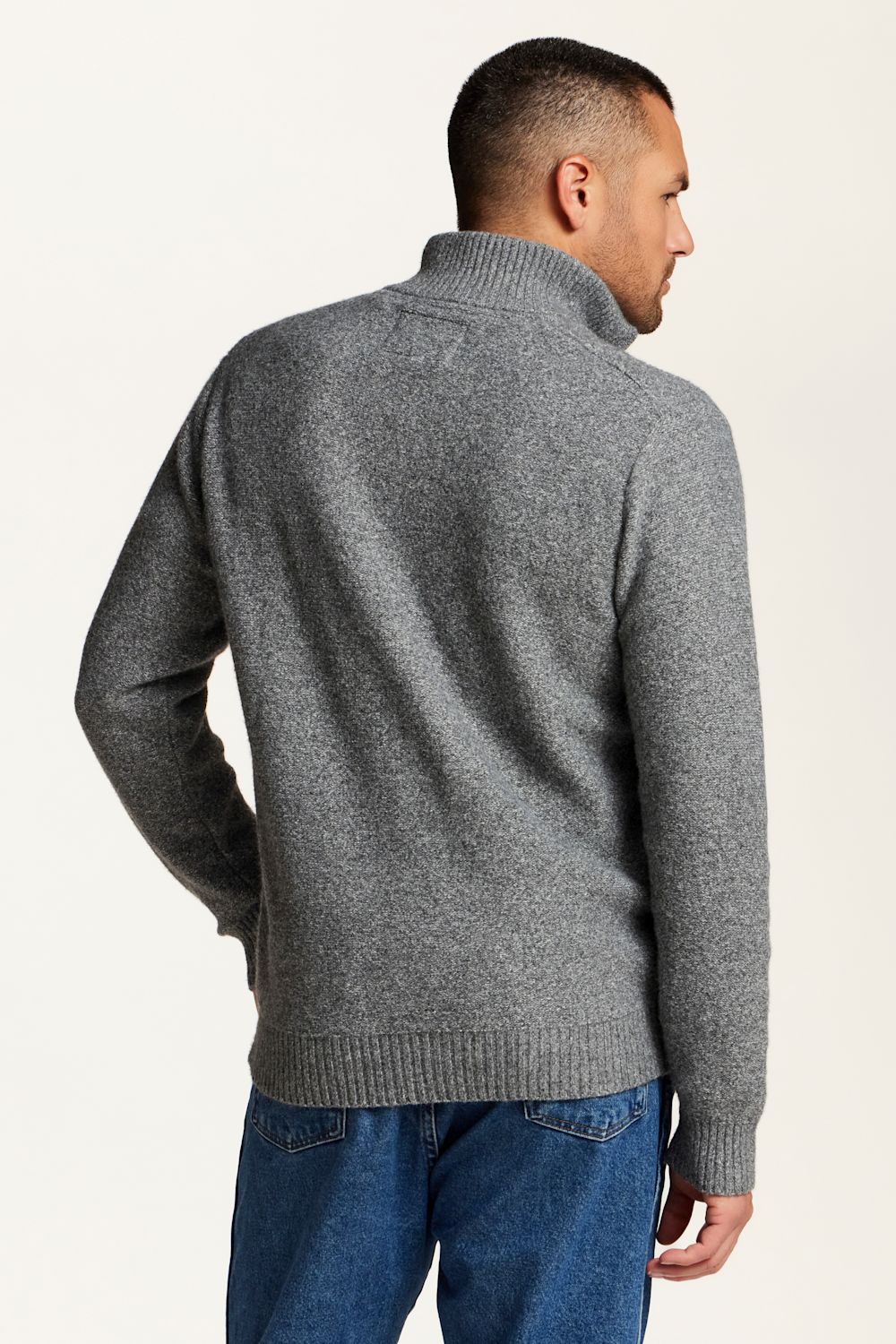 A man wearing a gray knit quarte zip sweater, shown from the back and side profile against a plain off-white background.