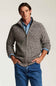 A man wearing a textured gray zip-up sweater over a light blue button-down shirt and blue jeans, standing against a plain light gray studio background.