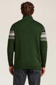 A man viewed from behind wearing a dark green knit sweater with white and gray geometric Fair Isle patterns on the upper sleeves, paired with dark gray jeans, against a light beige studio background.