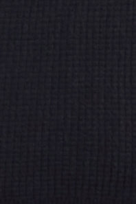 A close-up texture shot of a dark navy blue waffle-knit fabric.