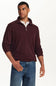 A man wearing a ribbed knit quarter-zip sweater in burgundy, layered over a white collared shirt and paired with blue jeans, photographed against a plain white studio background.