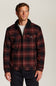 A man wearing a red and black plaid zip-up jacket with a dark corduroy collar, photographed against a plain light gray studio background.