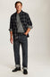 A man modeling a dark gray and black plaid overshirt over a gray t-shirt, paired with dark gray jeans and black shoes, against a plain light gray studio background.