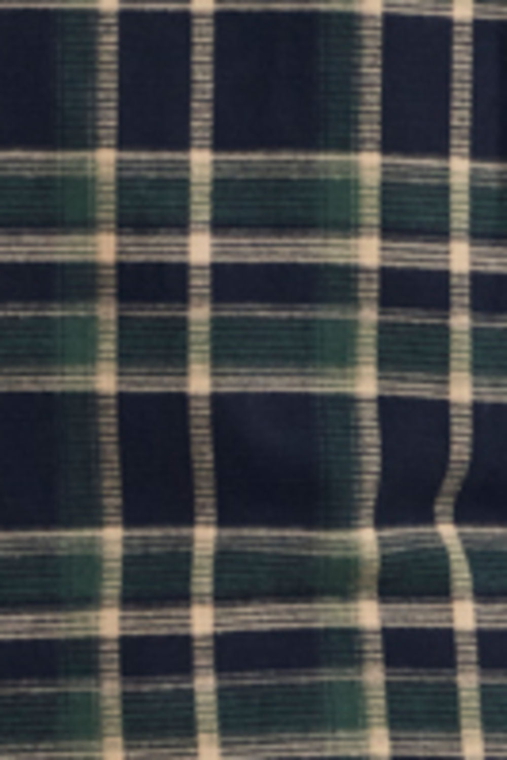 A close-up of a plaid fabric pattern with dark navy blue, forest green, and off-white stripes.