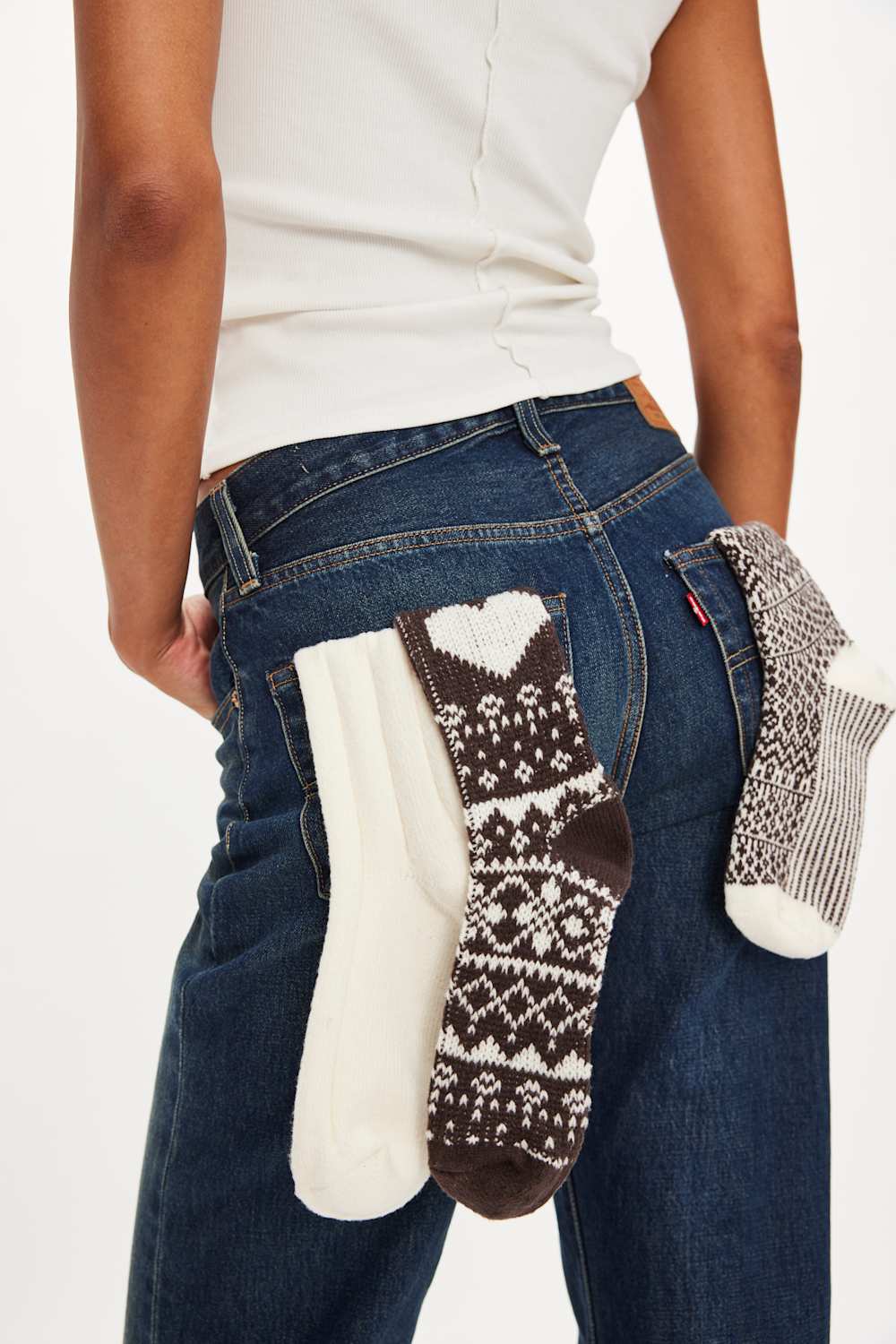 Person holding three pairs of patterned socks against a white background