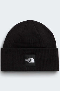 A black ribbed knit beanie hat featuring a black square patch on the front with the white 'THE NORTH FACE' logo, set against a light gray background.