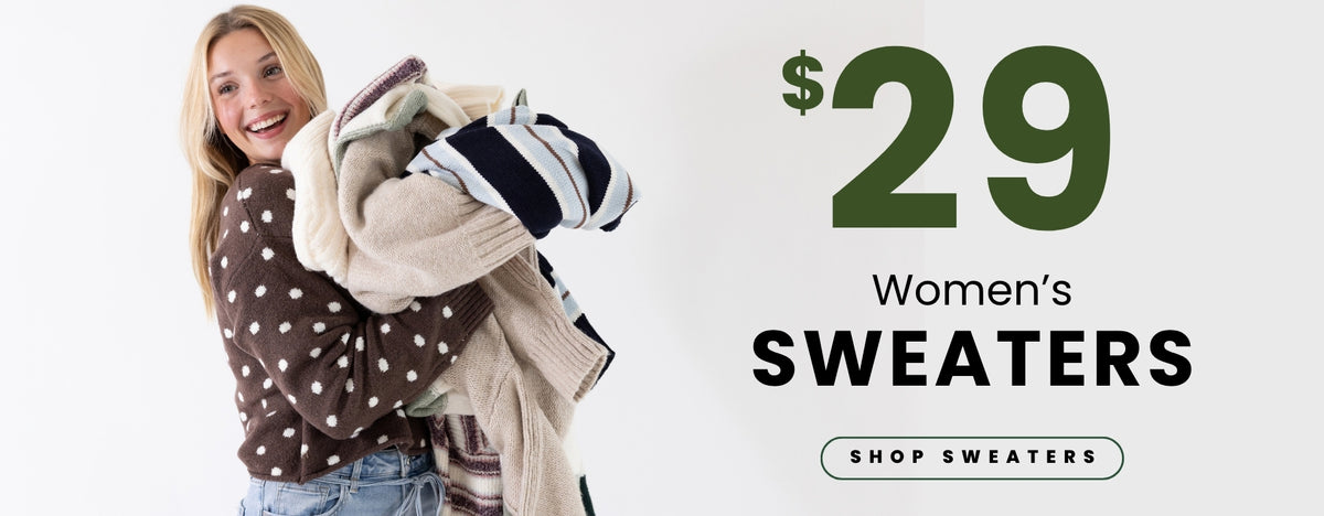 A smiling model holds a stack of cozy sweaters while wearing a brown polka-dot sweater and light-wash jeans. Text promotes women’s sweaters for $29 with a Shop Sweaters call to action.