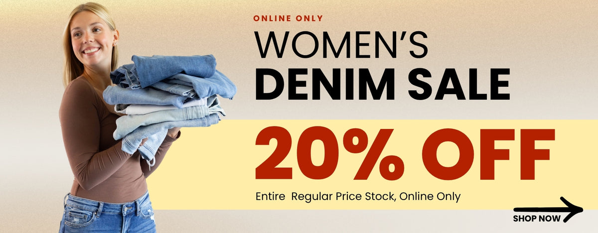 A promotional banner promoting an online only women's denim sale for 20% off. Text reads from top to bottom ONLINE ONLY WOMEN'S DENIM SALE 20% OFF Entire Regular Price Stock, Online Only also featuring a woman wearing a basic brown long sleeve top holding a stack of denim jeans. A black arrow with SHOP NOW call to action in the bottom right corner