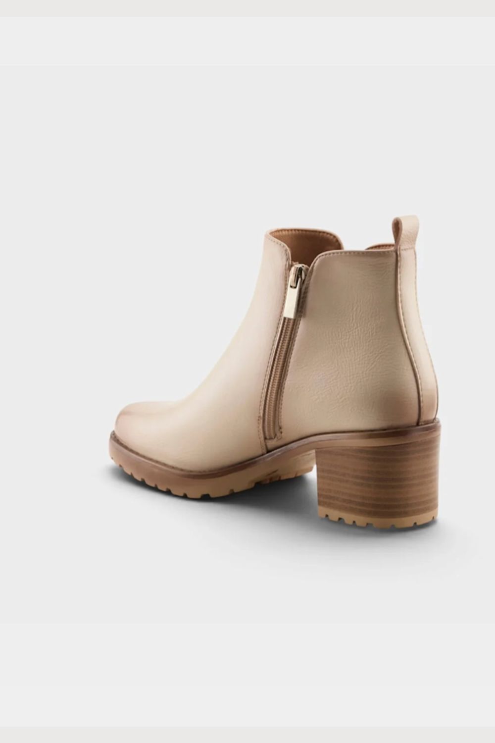 A beige faux-leather ankle boot with a block heel, side zipper, and pull tab, shown from a three-quarters rear angle on a light gray background.