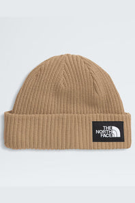 A tan ribbed knit beanie hat with a black rectangular patch on the front cuff featuring the white 'THE NORTH FACE' logo, shown against a light gray background.