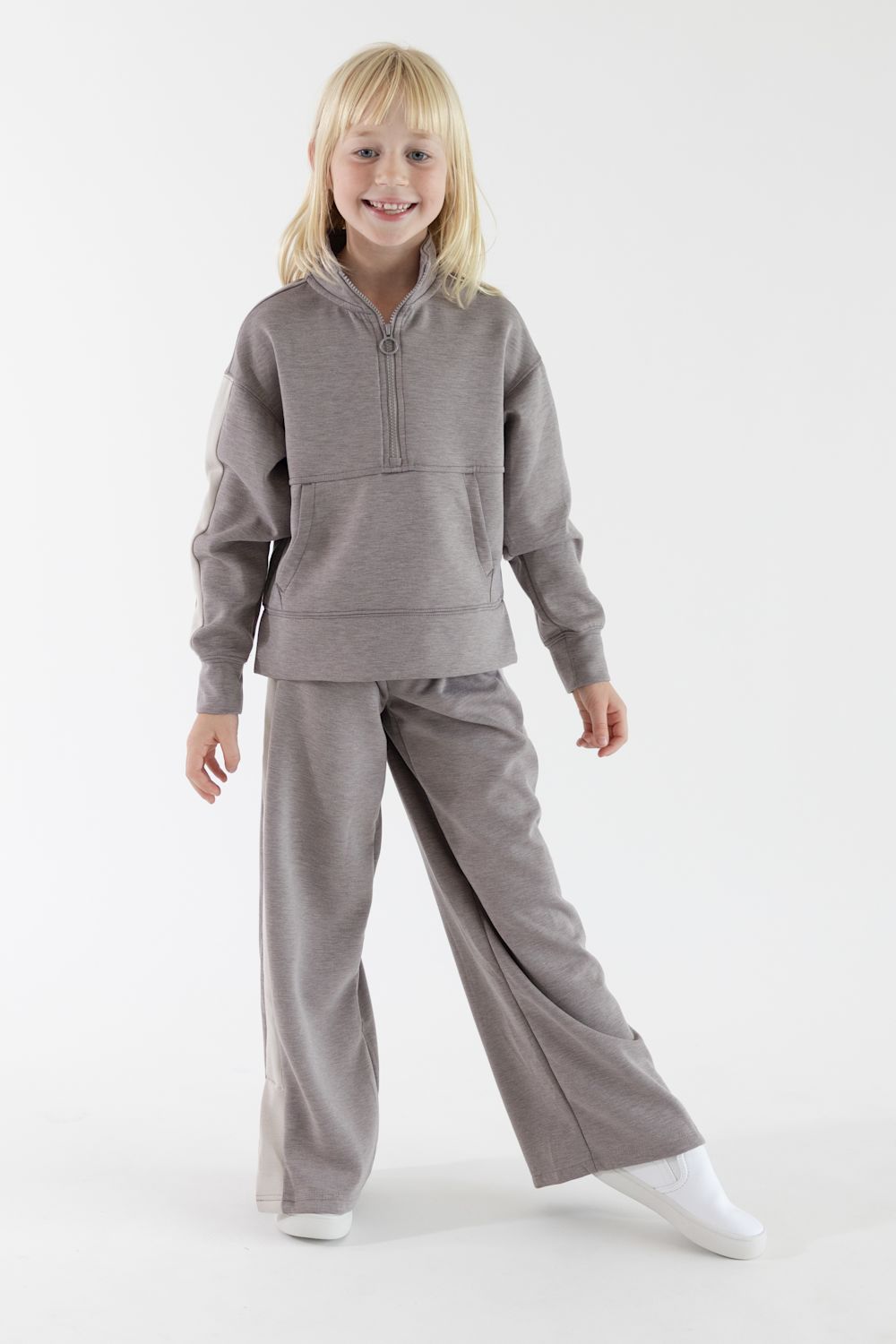 Young girl posing in a heather cocoa two-piece outfit featuring a long-sleeve half-zip mock-neck pullover with contrast stripe detail on the sleeves and matching wide-leg pants.