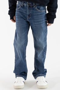 Front-facing view of a boy wearing Axel Jeans medium-wash straight-leg denim featuring light whiskering on the thighs, styled with white sneakers.