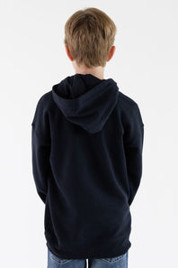 A child viewed from behind wearing a dark navy blue hoodie and blue jeans against a plain white background.