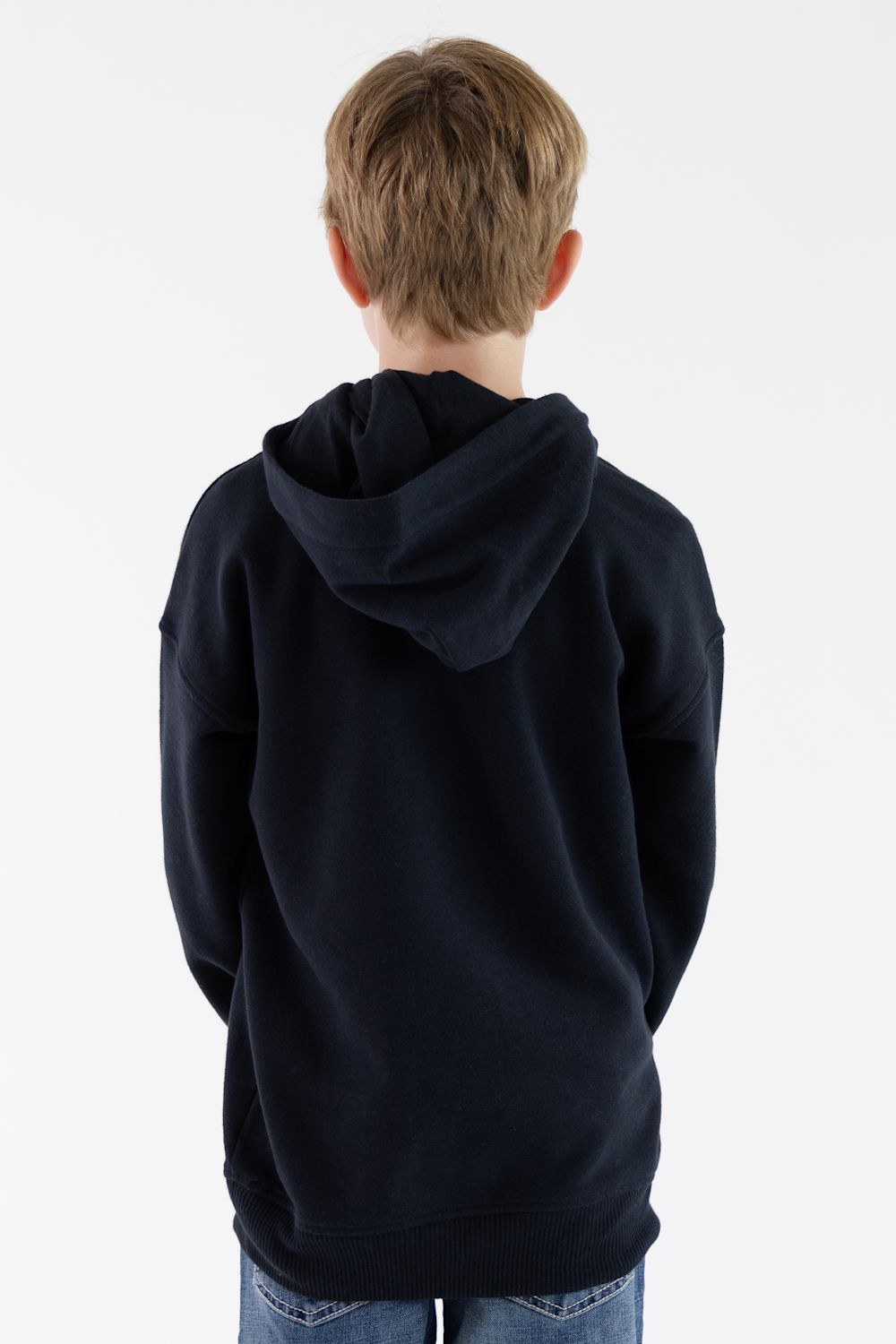 A child viewed from behind wearing a dark navy blue hoodie and blue jeans against a plain white background.