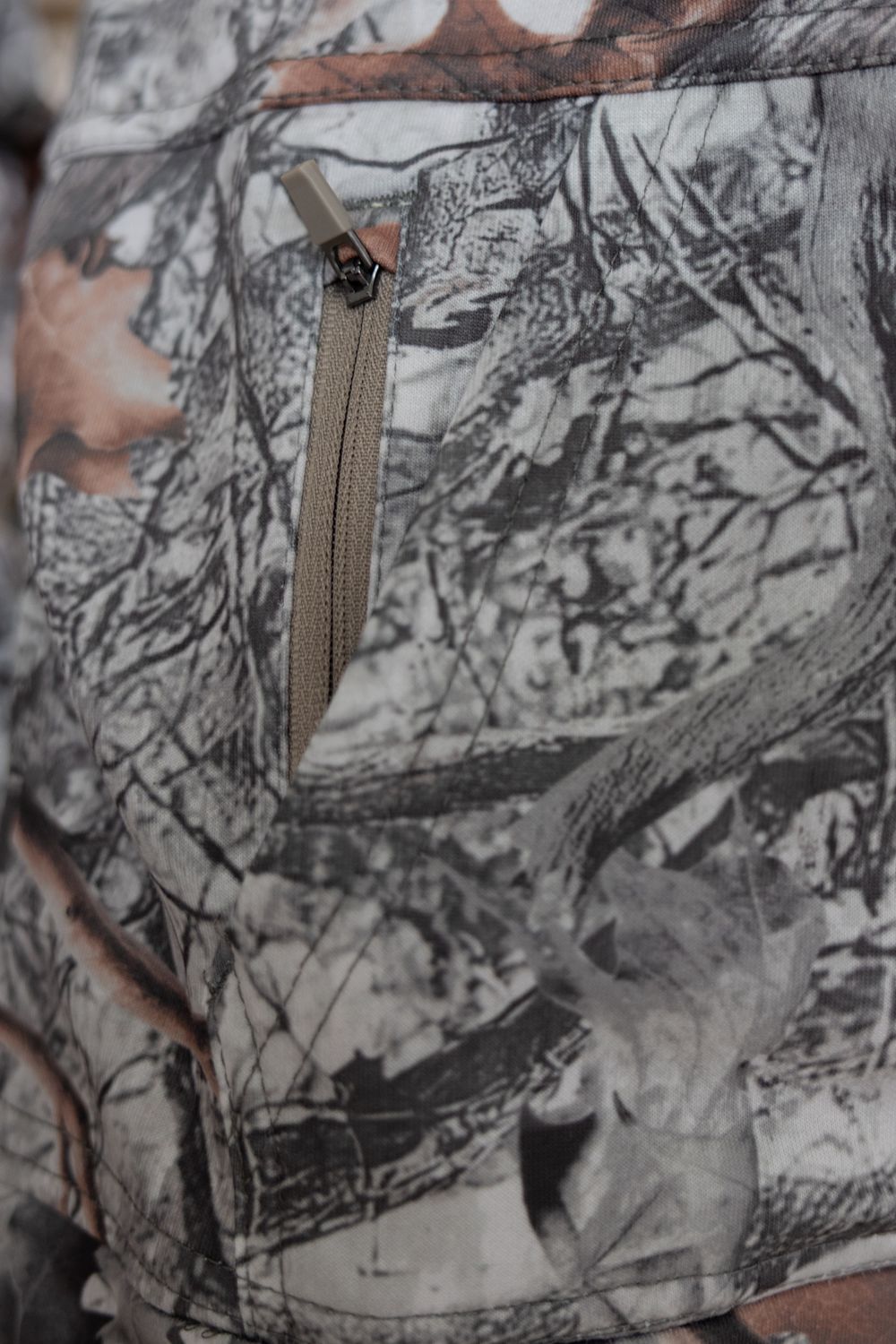 Close-up of the 90 Degree Youth Softlite Hoodie in Woods Print Camo highlighting the zippered pocket detail on the front kangaroo pocket.