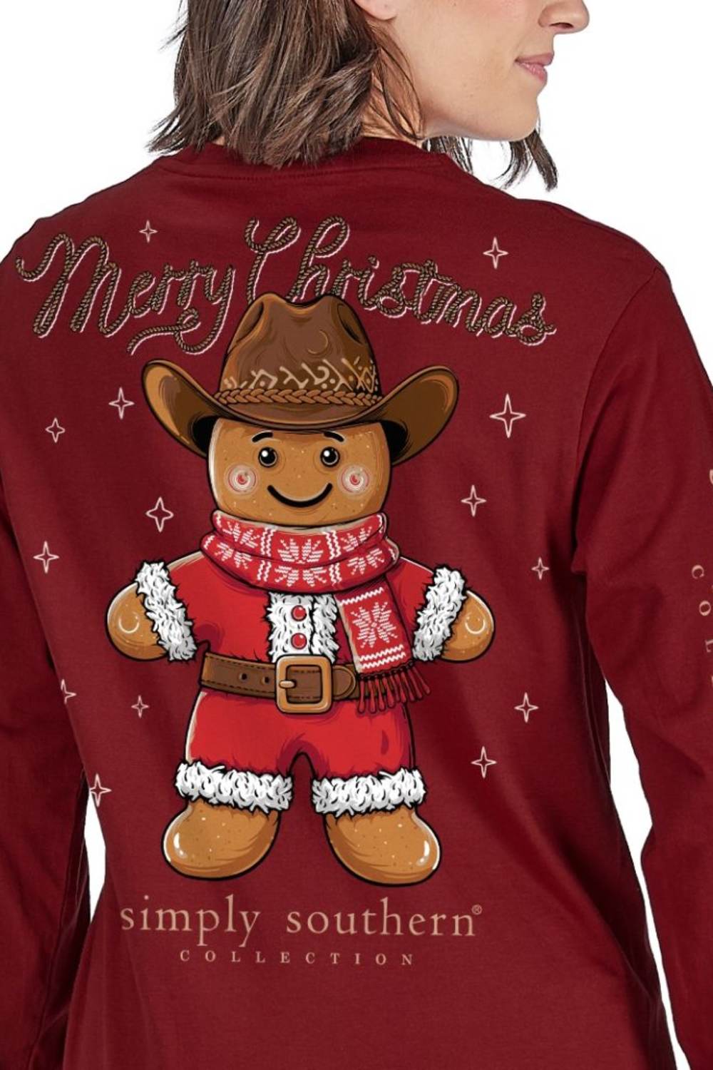 A woman wearing a dark red long-sleeve shirt, viewed from the back. The shirt features a large graphic of a gingerbread man wearing a cowboy hat and red sweater, with 'Merry Christmas' written above and 'simply southern COLLECTION' below.