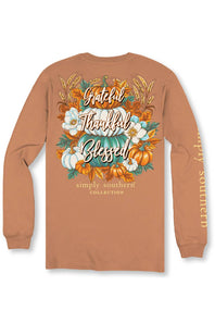 A long-sleeve t-shirt in a warm terracotta or rust color, shown from the back. The back features a large, detailed autumn graphic with pumpkins, white flowers, wheat, and the words 'Grateful Thankful Blessed' in script.