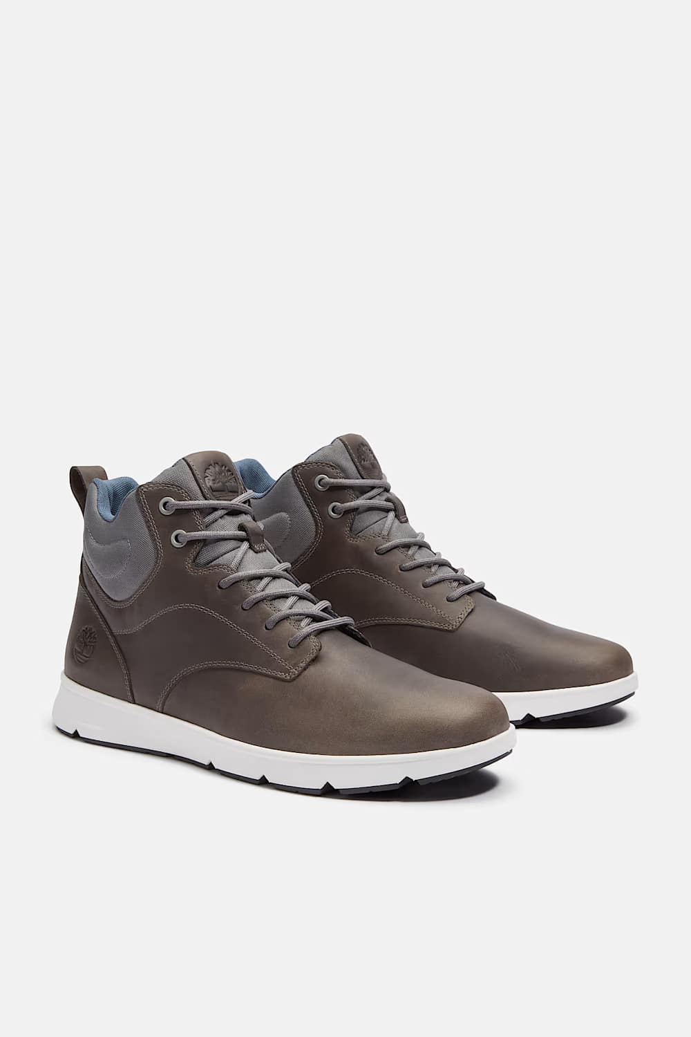 A pair of mid-top lace-up sneakers in a dark brownish-gray leather, featuring gray laces, a white midsole, and a light blue interior lining, shown against a light gray background.