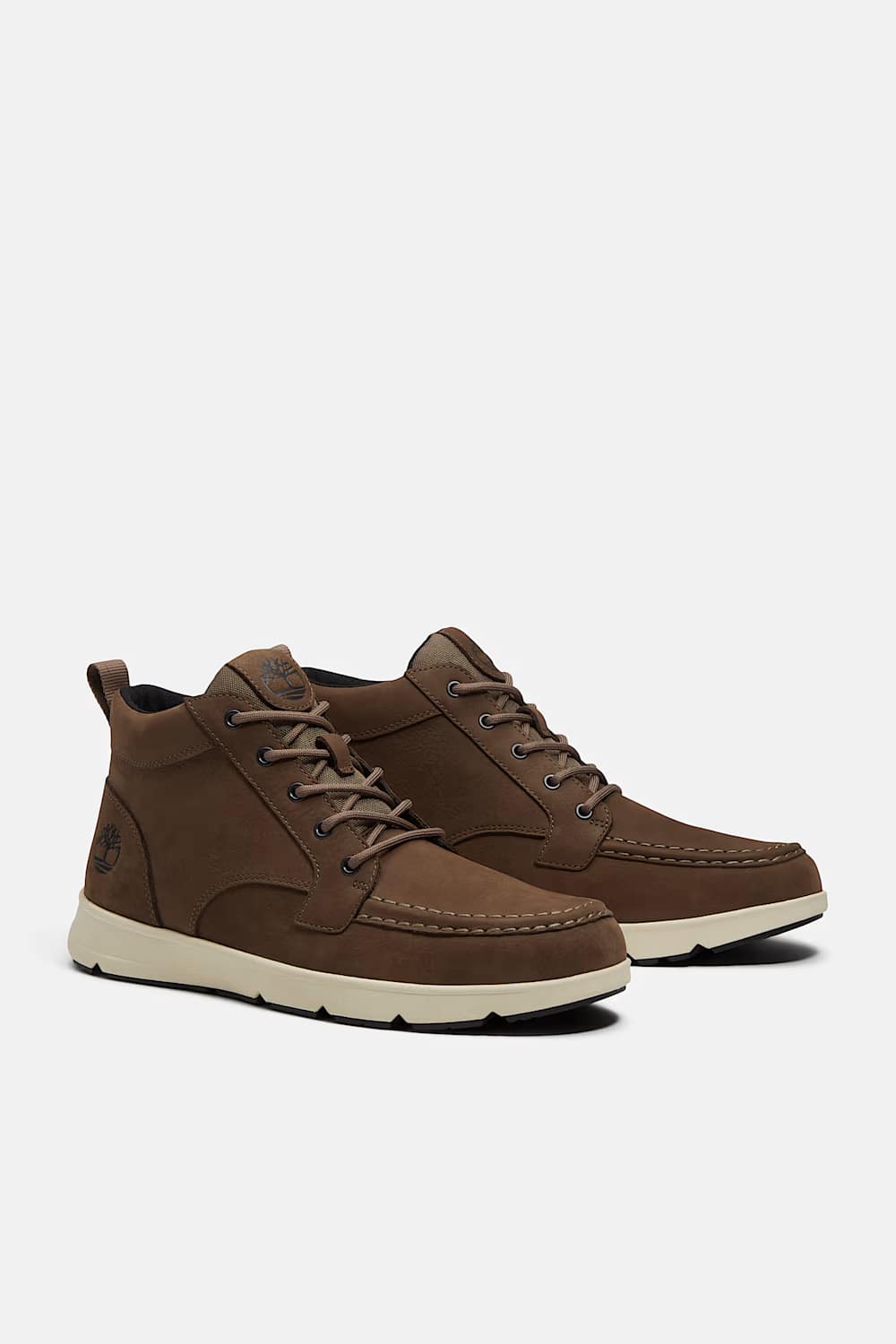A pair of brown suede and leather low-top lace-up shoes with off-white soles, displayed against a light gray background.