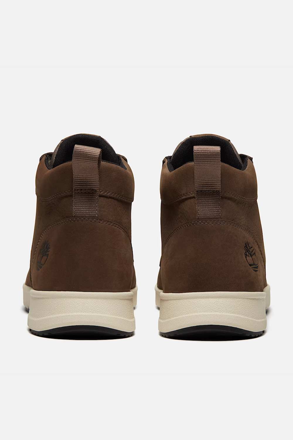 A pair of Timberland mid-top boots shown from the back, featuring brown suede uppers, pull tabs, and a cream-colored midsole.