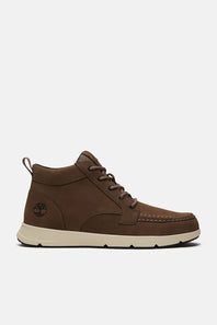 A pair of brown suede and leather low-top lace-up shoes with off-white soles, displayed against a light gray background.