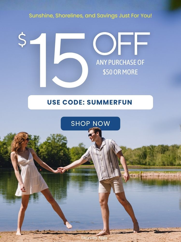 Man and woman holding hands on a lake beachfront; woman wearing a short white dress and the man wearing a camp collar button up shirt and shorts; text reads "$15 off any purchase $50 or more - use code: SUMMERFUN - exclusions apply - shop now"