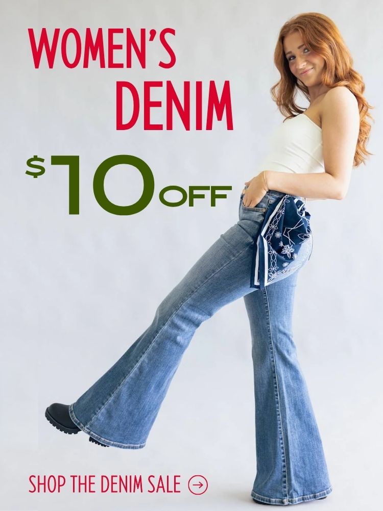 Women wearing blue denim jeans with a bandana accent and a basic white top kicking her leg up on a plain background with text that read "Women's Denim - $10 off - Shop the Denim Sale"